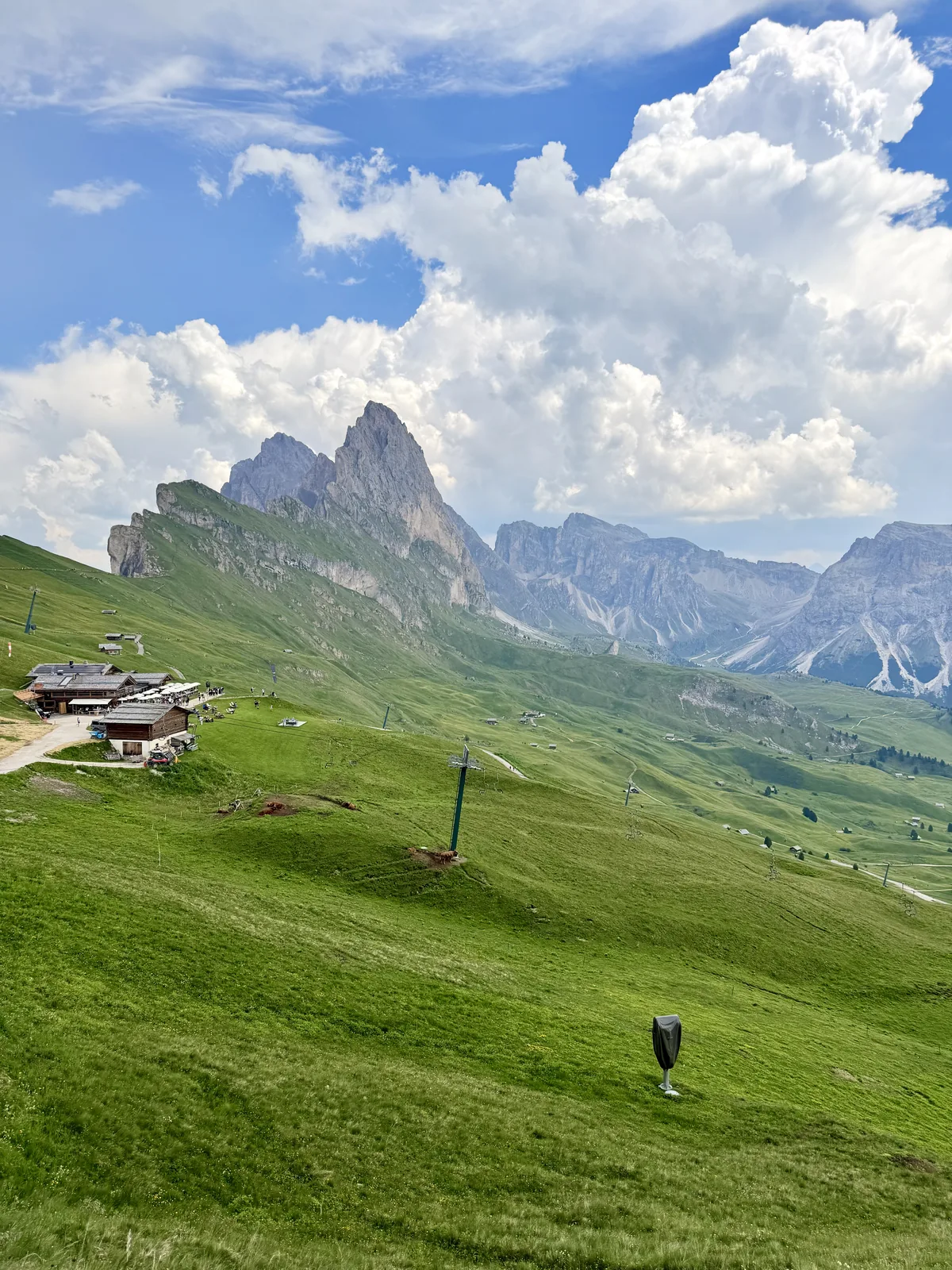 View of the rocky peaks of Seceda with a mountain refuge and cable car in the background, in the Dolomites