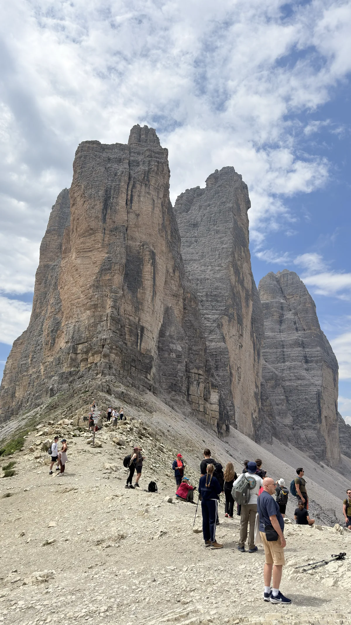 The three peaks of Tre Cime di Lavaredo seen up close, with hikers on the trail, in the Dolomites