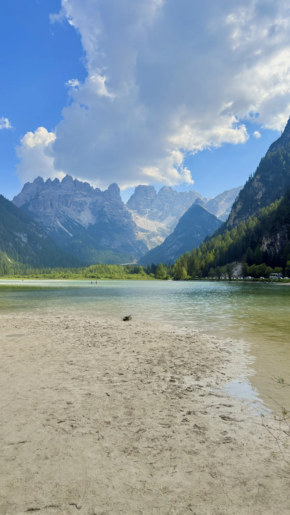 Lake with a light sandy beach and mountains in the background, one of the lakes visited on the third day in the Dolomites