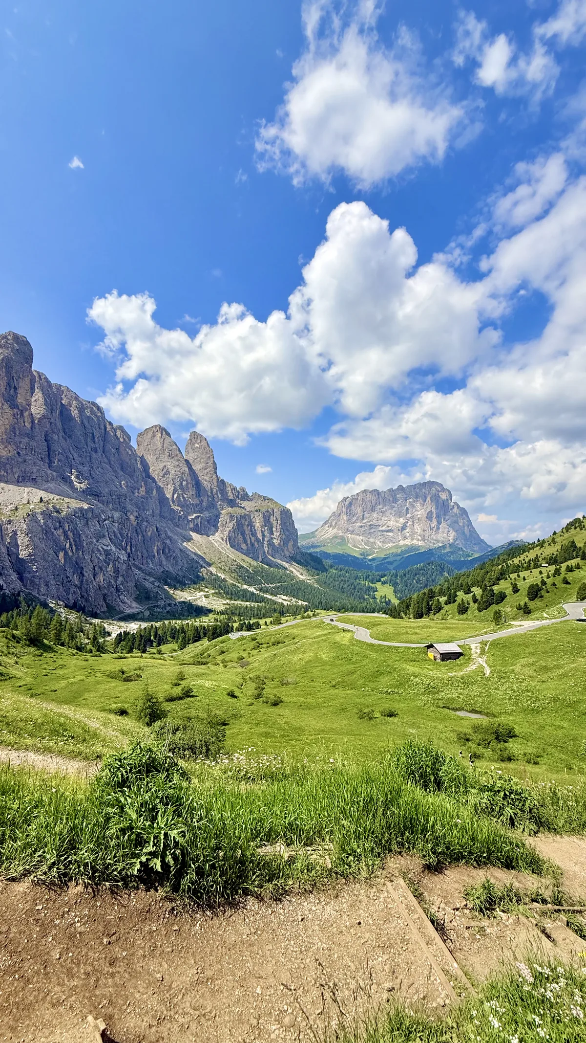 Scenic road surrounded by mountains and a green valley in the Dolomites