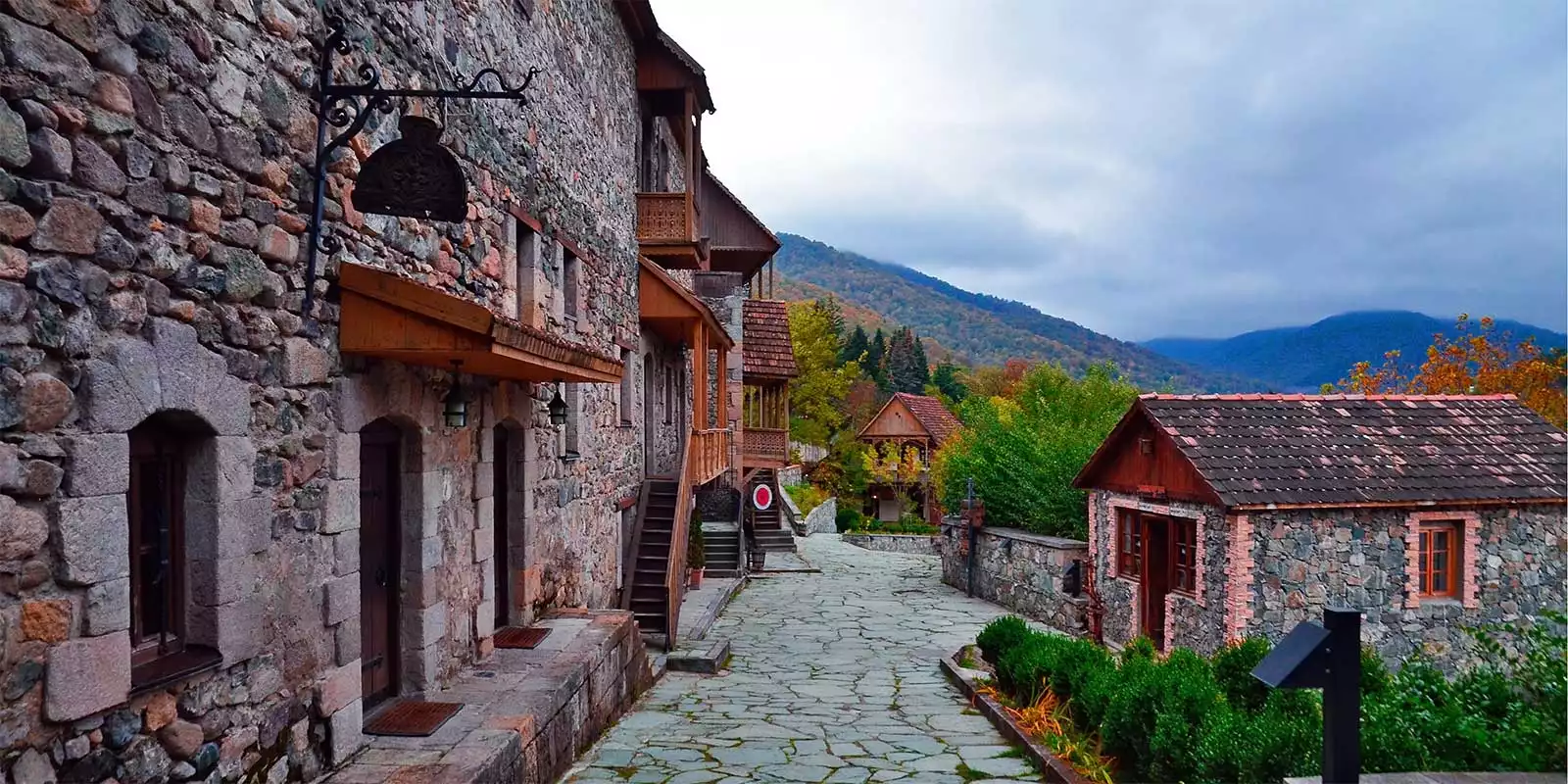 Rua de pedra com casas tradicionais restauradas e cafés na área histórica de Old Dilijan, Armênia