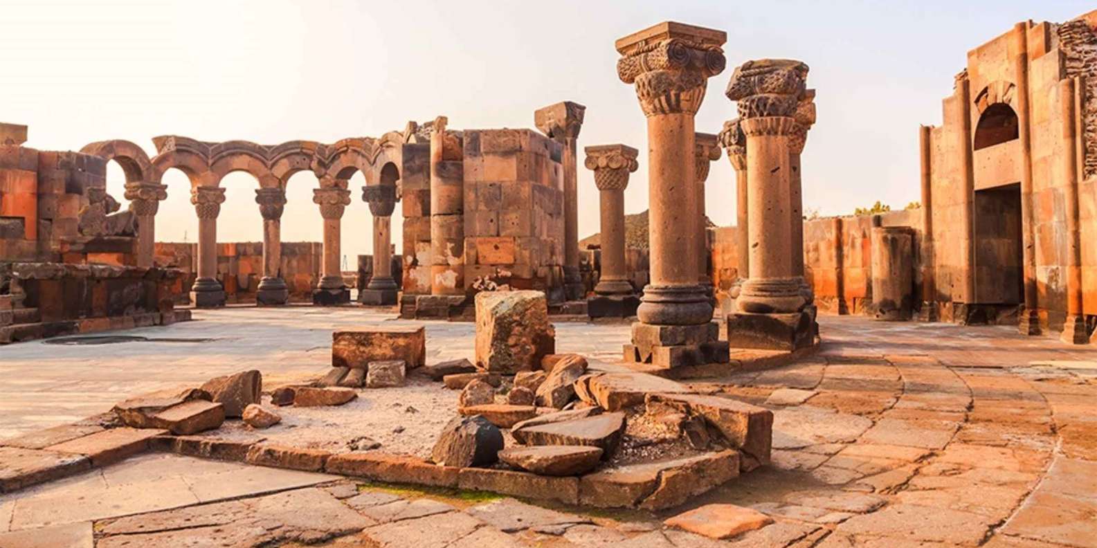 Ruins of Zvartnots Cathedral with stone columns and arches in an open area, near Yerevan, Armenia