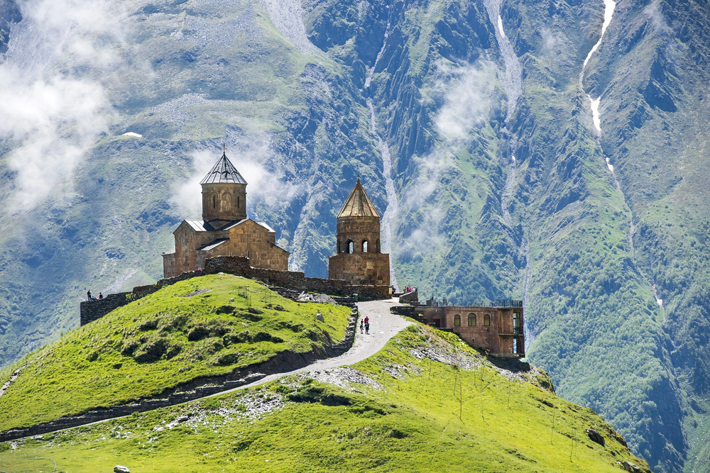 Gergeti Trinity Church no alto da colina com as montanhas nevadas do Cáucaso ao fundo, Kazbegi, Geórgia