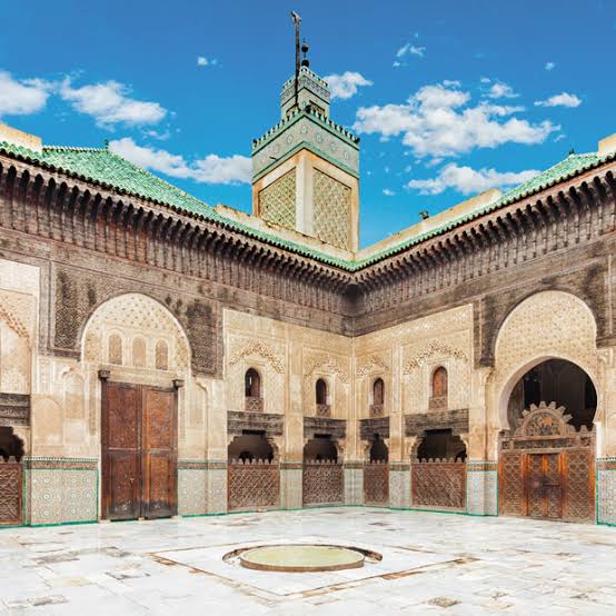 Interior da Medersa Bou Inania em Fez com azulejos zellij, estuques entalhados e pátio central, Marrocos