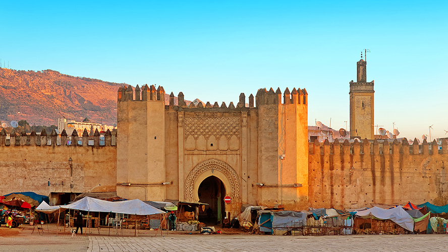 Ruas estreitas da Medina de Fez com arcos, lojas e movimento de pedestres, Marrocos
