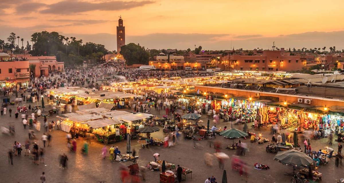 Praça Jemaa el-Fna iluminada à noite com barracas, movimento e a Koutoubia ao fundo, Marrakech, Marrocos