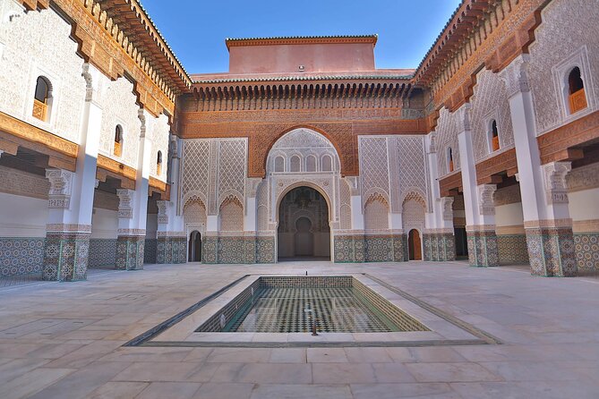 Pátio interno da Medersa Ben Youssef em Marrakech com azulejos detalhados e madeira esculpida, Marrocos
