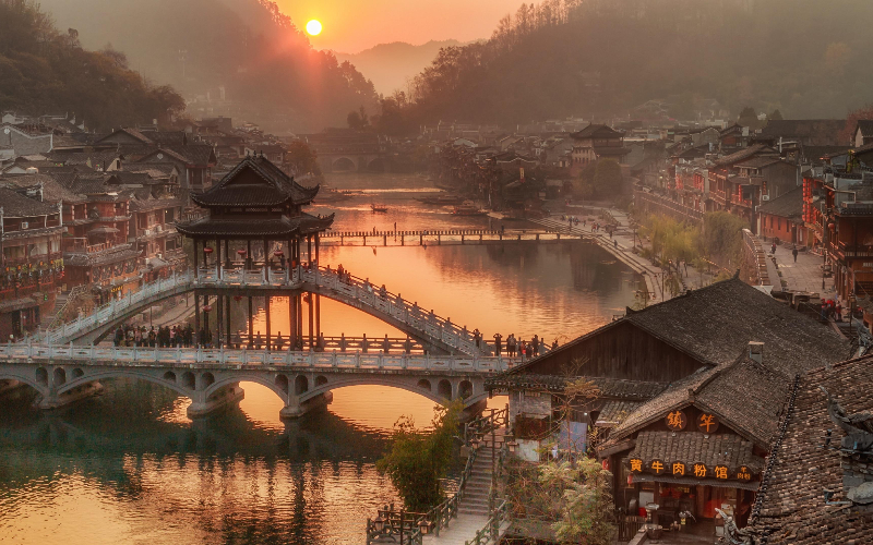 Ponte Arco-íris sobre o rio Tuojiang em Fenghuang ao pôr do sol