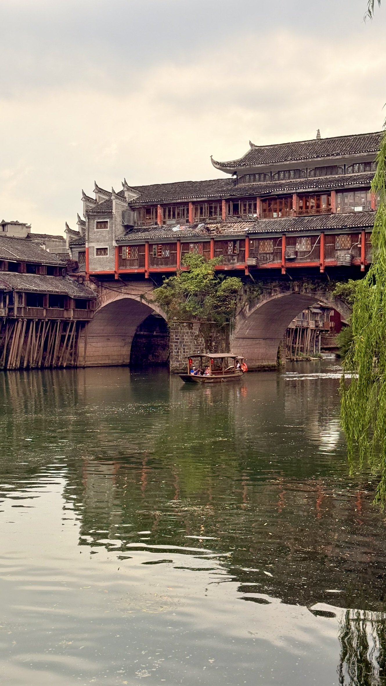 Rainbow Bridge in Fenghuang Ancient Town with a boat on the Tuojiang river in Hunan