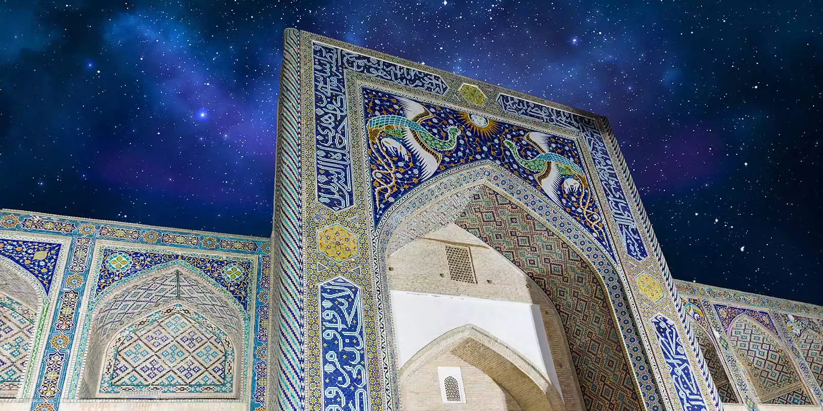 Lyabi-Hauz à noite com reflexos das luzes no lago e movimento local em Bukhara, Uzbequistão