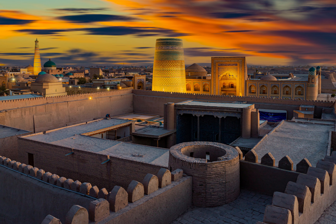 Centro histórico de Khiva iluminado à noite com minaretes ao fundo, Uzbequistão