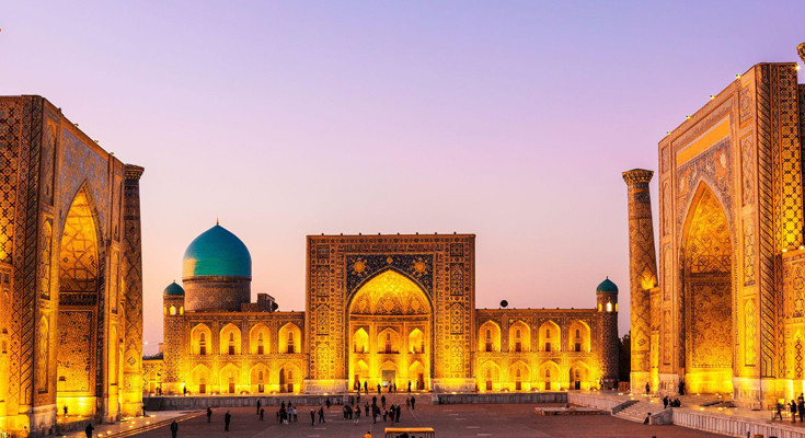 Praça do Registan iluminada à noite em Samarkand, Uzbequistão