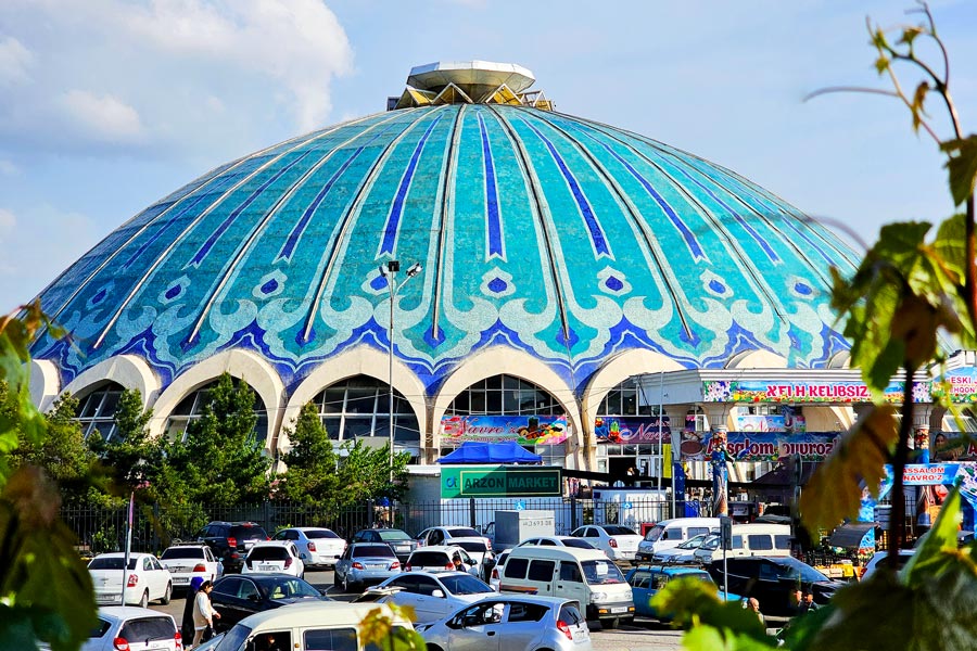 Chorsu Bazaar com a grande cúpula azul e o movimento do mercado em Tashkent, Uzbequistão